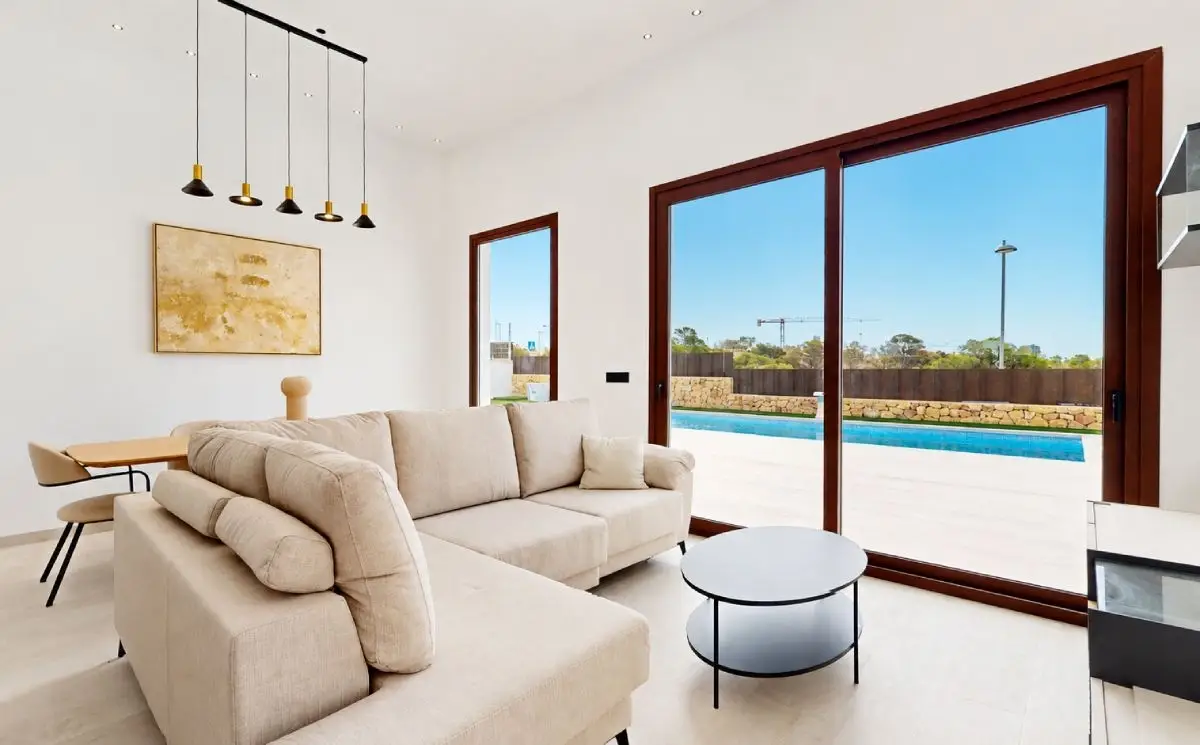 Salón moderno y luminoso de una vivienda inteligente con grandes ventanales y vistas a la piscina en la Costa Blanca.